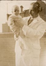 A medium shot of a Doctor standing outside holding a baby. Doctor and Baby, 1928
