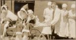 A medium shot of three Nurses watching a Doctor push a trolley on which two people dressed as Father Christmas are sitting. Christmas Celebrations, 1928