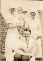 Long shot of two Nurses standing holding infants and a Doctor sitting with an infant outside posing for the camera. The Children's Corner Ward, 1928