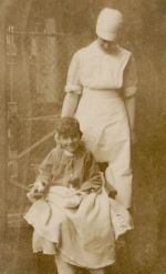 A long shot of a Nurse standing behind a child sitting in a chair with a blanket over his lap. Nurse and Child, 1928