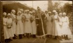 A group of Nurses standing around a person dressed as Father Christmas. Some of the Nurses are holding musical instruments. Christmas Celebrations, 1928