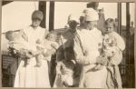 Medium shot of three Nurses holding infants and young patients on the balcony posing for a photo. Nurses Holding Babies, 1928