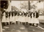 A long shot of a group of twelve Nurses standing outside in the street all with their capes on. Nurses Outside the Hospital, 1928