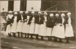 A long posed shot of eleven Nurses standing outside. Row of Nurses, 1928