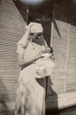A medium shot of a Nurse standing and holding a baby taken outside in the sunshine. Portrait of a Nurse Holding an Infant, 1928