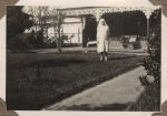 A long shot of a Nurse standing outside in the garden with a building in the background. Nurse on the Lawn, 1928