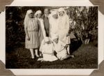A long shot of four Nurses standing with a Doctor and two Nurses sitting on the grass in the garden. Staff on the Lawn, 1928