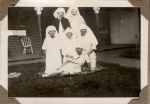 A long shot of six Nurses on a rug in the garden. Two are standing at the back. Three are kneeling and the last is sitting. Staff on the Lawn, 1928