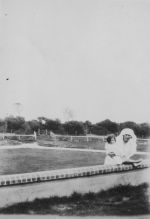 Long shot of a Nurse with a young child standing outdoors behind a low wall posing for the camera. Nurse and Child, Circa 1940