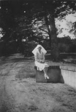 Long shot of a Nurse seated outdoors on the end of a low wall posing for the camera. Nurse on Wall, Circa 1940
