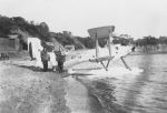 Long shot of three adults posing for the camera beside a stationary seaplane on a beach. Seaplane Visitors, Circa 1940