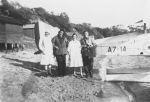 Long shot of four adults posing for the camera beside a stationary seaplane on a beach. Seaplane Visitors, Circa 1940
