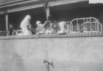 Medium shot of group of medical staff with patients in cots outside. Balcony View, Circa 1940