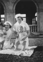 Medium shot of two kneeling Nurses each holding infants posing for the camera. Nurses and Children on the Lawn, Circa 1940