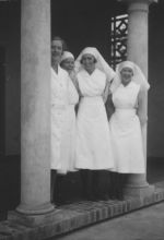 Long shot of four Nurses standing under an archway posing for the camera. Nurses, Circa 1940