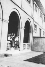 Long shot of four children seated under an archway posing for the camera. One child has an arm in a cast. On the Balcony, Circa 1940